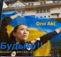 大阪城を背景に女性がウクライナの旗を両手で掲げている。